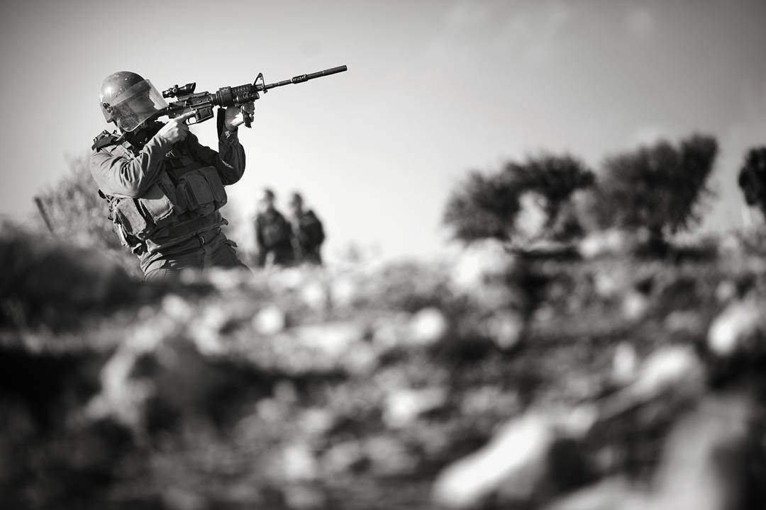 Taking aim, but not firing an IDF soldier seeks to quiet a crowd of protestors near the Palestinian town of Bil'in in th