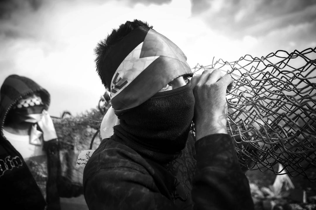Claiming to have torn down another section of the wall, protestors carry it to throw at the IDF soldiers protecting the 